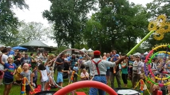 As families and friends gather around a charming bubble artist wielding a giant yellow bubble wand that sprays hundreds of bubbles in seconds they laugh in awe while donning their love of diversity in celebration of humanity and a very merry moment in Maryland.