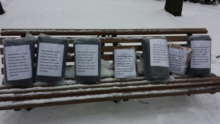 Blankets and gift cards line a bench, waiting to keep the homeless warm.